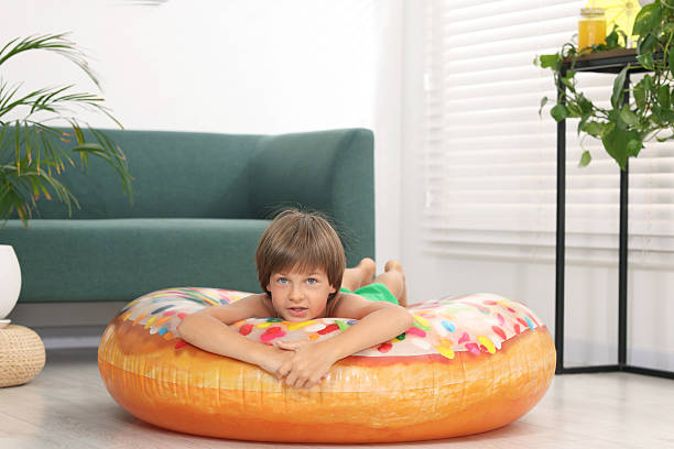 istock Dreaming about vacation at sea. Little boy on inflatable ring indoors 2245222575