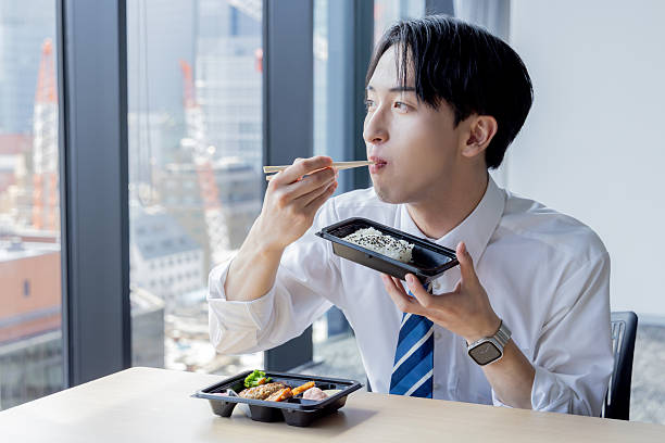 Asian businessman eating takeaway lunch