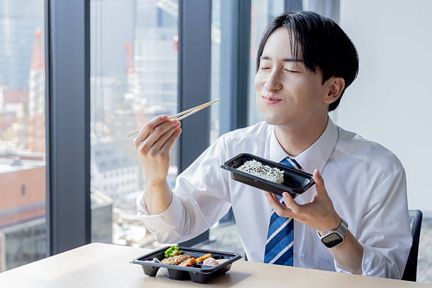 Asian businessman eating takeaway lunch