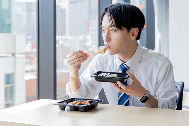 Asian businessman eating takeaway lunch