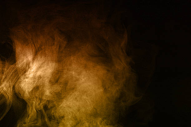 Golden orange smoke texture rising on dark background, creating abstract swirl patterns with dramatic lighting. Perfect for design projects, energy concepts, fire visuals, and artistic digital.