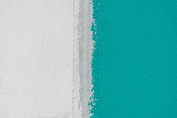 Close up of a white and turquoise painted wall surface with a sharp dividing line, representing color contrast, modern minimalism, home renovation, creativity, and artistic interior design background.