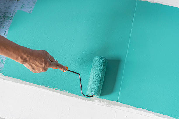 istock Hand using paint roller applying turquoise color on wall for home renovation and interior design concept 2245235400