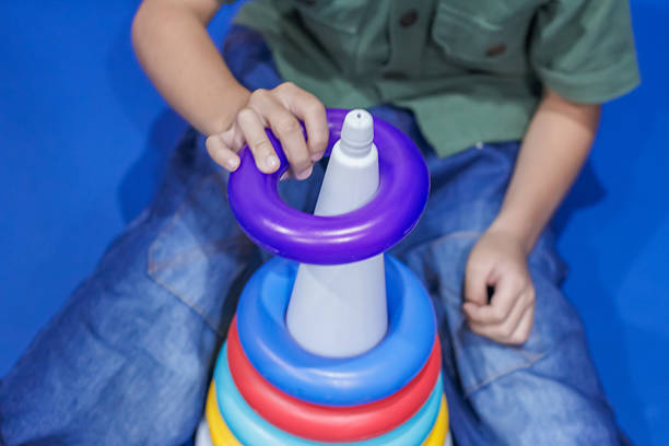 a child playing with a colorful stacking ring toy, promoting hand-eye coordination and early learning skills