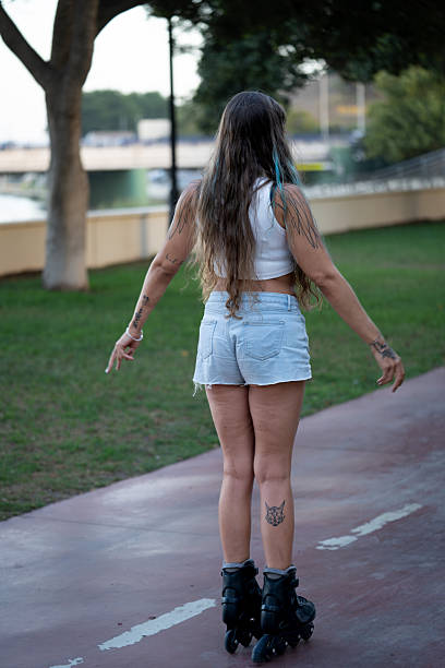 Young woman rollerblading outdoors on a paved path in a park, enjoying leisure time and an active summer lifestyle