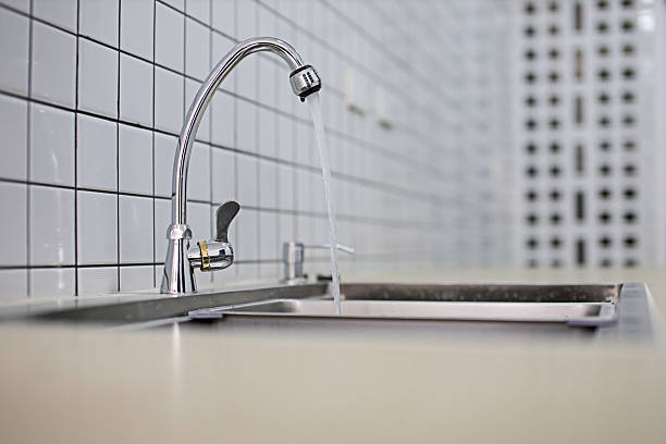 The silver faucet in the kitchen was turning on.