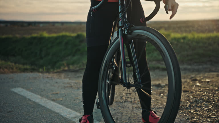 Young Caucasian Female Cyclist Checking Bicycle on Countryside Road