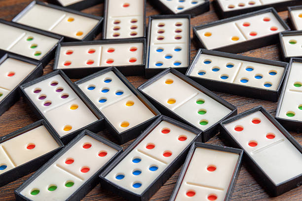 Playing dominoes at a wooden table for fun activity. White domino blocks. Board game for entertainment friends. Domino set.