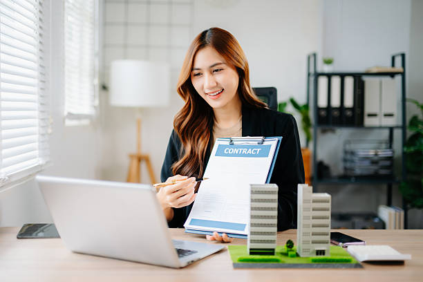 istock Asian real estate agent showing and explaining contract with condo models in modern office, representing property sales, investment, agreement, and business negotiation. 2245245488