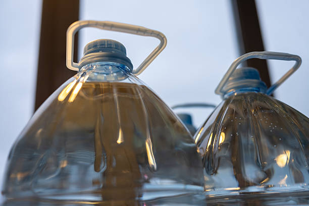 Low-angle shot of large transparent plastic jugs with pure drinking water. A concept for hydration, emergency supply, stock, and storage.
