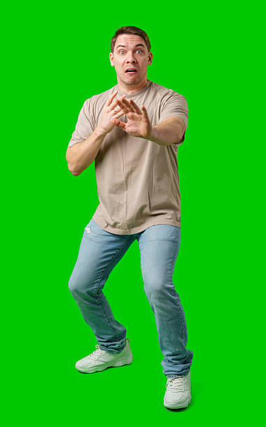 istock Man expressing fear while standing against a bright green background 2245255101