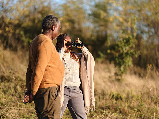 istock Black senior woman using binoculars with her husband in autumn day. 2245257763