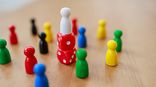 istock Leadership concept with recruitment strategy shown by white figure standing on dice surrounded by game pieces on wooden surface 2245264258