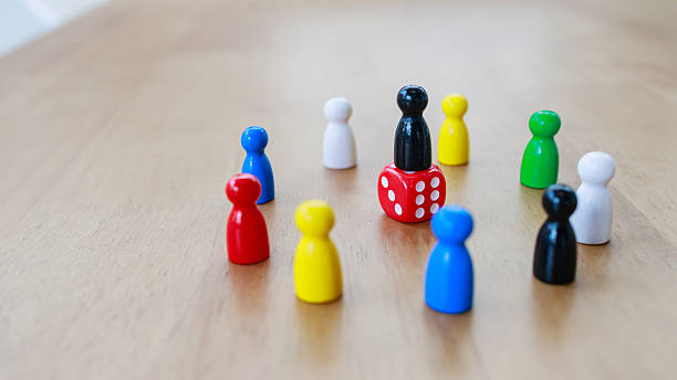 istock Leadership concept with recruitment strategy shown by black figure standing on red dice surrounded by game pieces in circle 2245264260