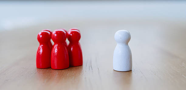 istock Leadership recruitment concept with single white figure separated from group of red figures on wooden surface symbolizing teamwork and decision 2245264308