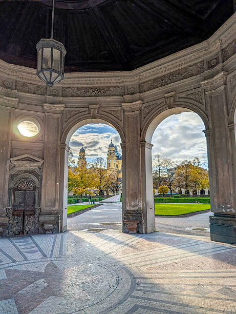 Munich, Germany,  November 3, 2025. Diana Temple interior arches framing the expansive Hofgarten and the distinctive domes of Theatinerkirche in Munich, Germany, in autumn