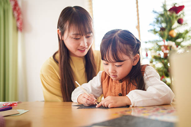 istock Mother Helping Daughter Write a Holiday Card 2245267982