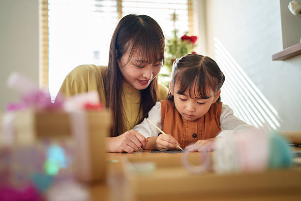 istock Mother Helping Daughter Write a Holiday Card 2245268139