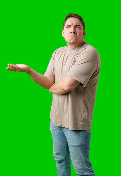 istock A man stands with arms crossed and a thoughtful expression in front of a green screen 2245268565