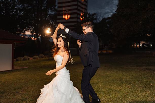 Bride and groom enjoying their first dance on grass under evening sky