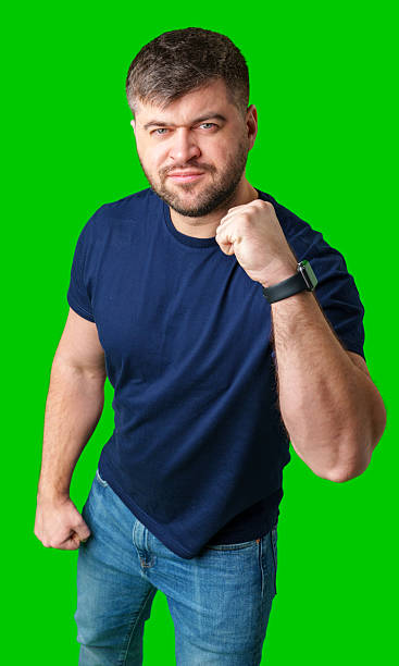 istock A strong man with fists raised, smiling confidently, on a bright green background 2245270970