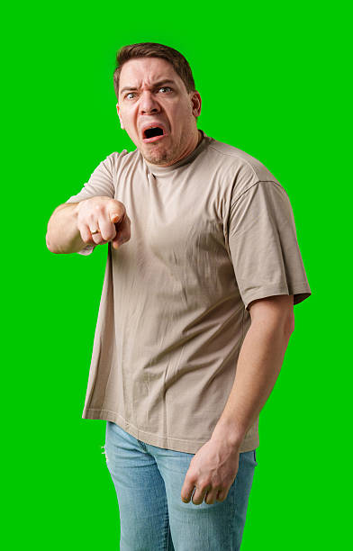 istock Man expressing anger and pointing in a plain t-shirt with a bright green background 2245272116