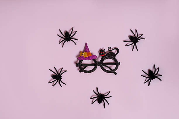 istock Spiders and carnival glasses for Halloween celebrations on a lilac background 2245272750
