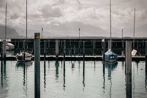 Lindau, Germany – February 10, 2023: Moody marina with sailboats and Alpine mountains