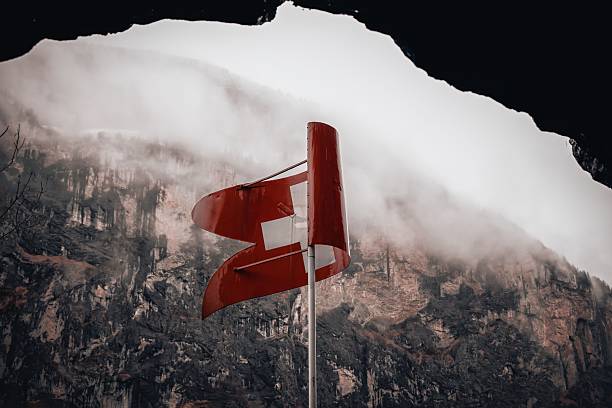 Swiss flag waving against a misty mountain backdrop, capturing the essence of Switzerland's natural beauty.