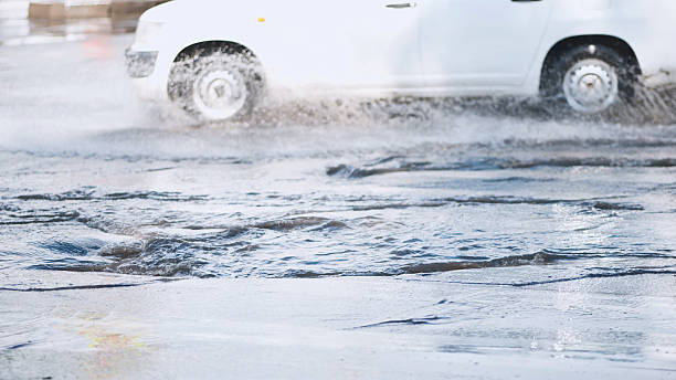 istock Speeding white vehicle splashing through large roadside puddle, spraying water dramatically with high energy motion 2245278292