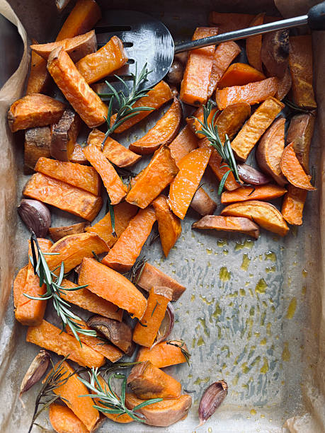 Delicious baked sweet potatoes with rosemary, just from the oven, ready to eat. Healthy and vegetarian food. Overhead view.