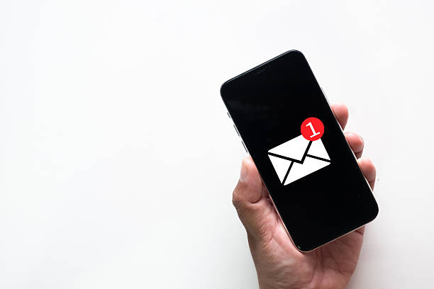 istock Hand holding a smartphone with one new email (e-mail) notification icon on the screen. Top view on white background. 2245285092