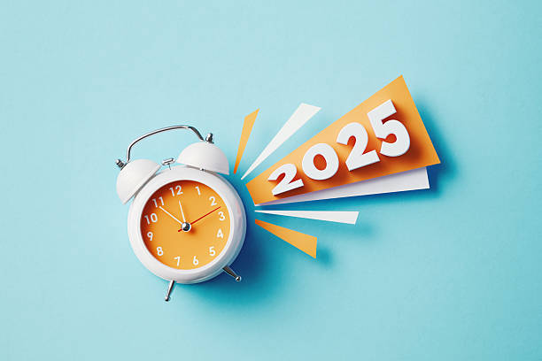 istock 2025 Sitting Next To A White Alarm Clock On Blue Background 2245290186