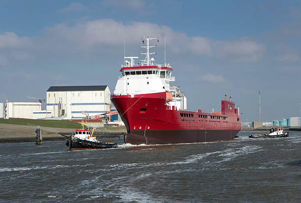 istock Tug boats pulling a freightship in the harbor. Shipping navigation in the Netherlands 2245290309