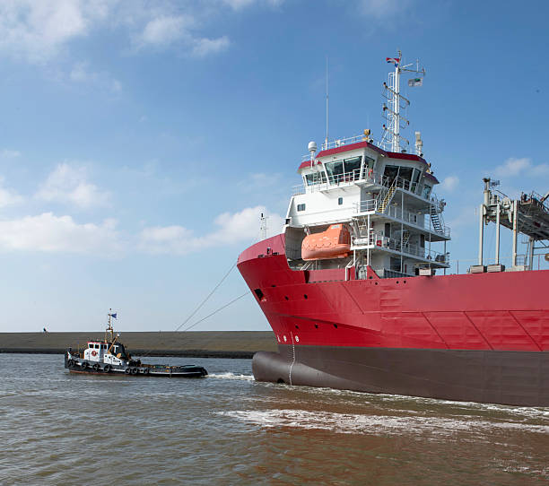Tug boats pulling a freightship in the harbor of Harlingen Friesland. Shipping navigation in the Netherlands