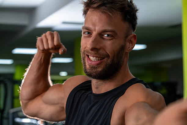 istock Smiling muscular man flexing bicep at gym, confident and proud 2245290740