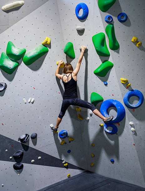 istock Female Climbs Indoor Rock Wall With Bright Holds 2245292002