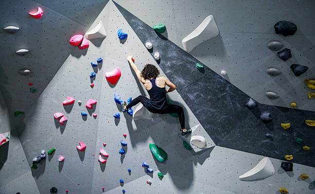 istock Climber On Indoor Rock Wall With Colorful Holds 2245292064
