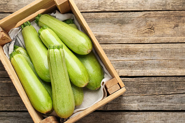 istock Fresh ripe zucchinis in crate on wooden table, top view. Space for text 2245292350