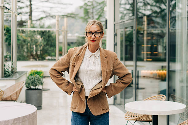 istock Confident blonde woman in beige blazer posing outdoors at a modern cafe setting 2245292977