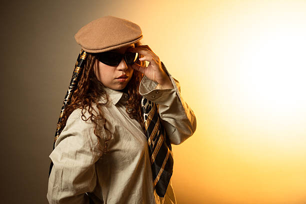 Stylish young adult woman posing with beret, sunglasses and patterned scarf in warm light
