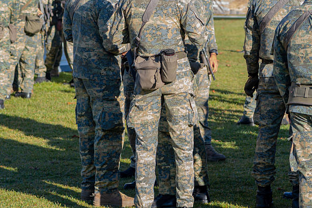 istock Several soldiers in camouflage uniforms are standing in a group on a grassy field 2245295419