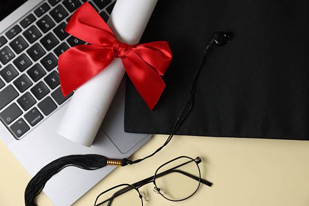 istock Graduation cap, laptop, diploma and glasses on beige background, flat lay 2245297303