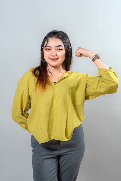 istock Young woman confidently smiling while flexing her arm, expressing strength, positivity, and determination. Ideal for empowerment, success, motivation, and self-confidence themes. 2245297603