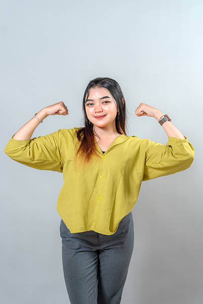istock Young woman confidently smiling while flexing her arm, expressing strength, positivity, and determination. Ideal for empowerment, success, motivation, and self-confidence themes. 2245299052