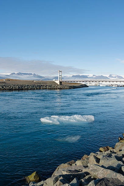 istock A serene scene of a bridge spanning calm waters, with mountains afar. 2245300934