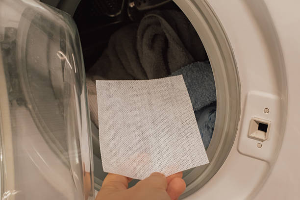 istock Hand placing a color catching laundry sheet into the washing machine drum with clothes. Preventing dye transfer and protecting garments from running colors during the wash cycle 2245301349