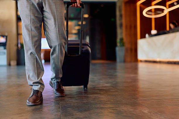 istock Businessman entering hotel lobby pulling luggage 2245302851