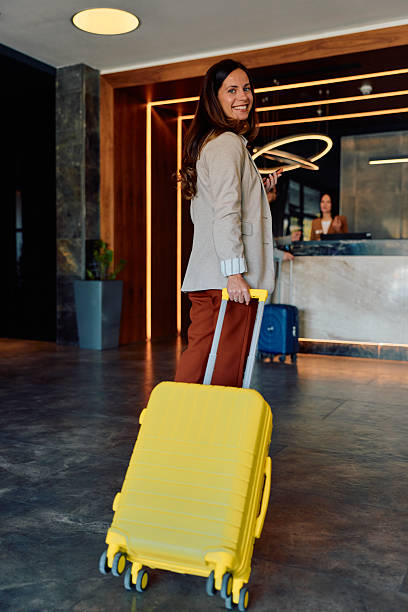 istock Smiling woman pulling suitcase arriving at hotel check-in 2245303248