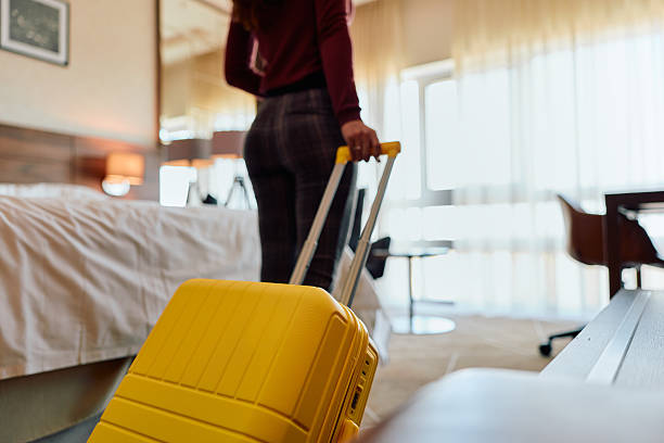 istock Woman pulling yellow suitcase entering hotel room for travel 2245303359